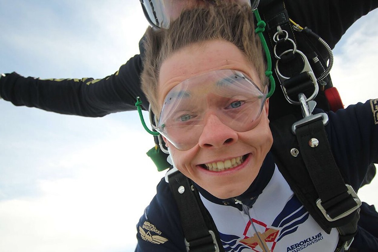 A smiling tandem skydiving student in freefall