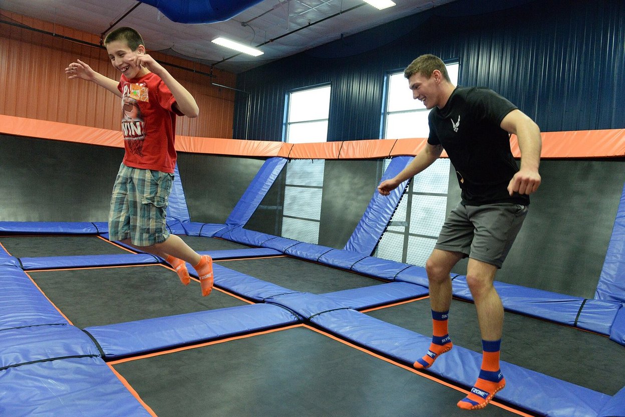 Kids and an adult jumping at an indoor trampoline park