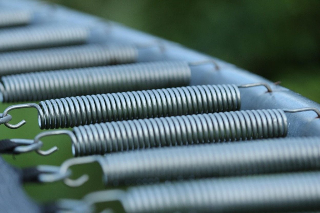 Row of metal coil springs along the edge of a trampoline mat.