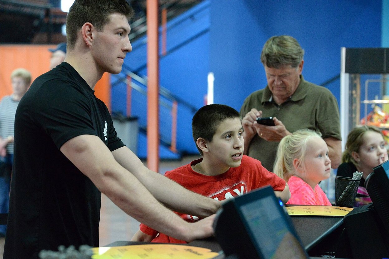 Kids jumping on connected trampolines inside a bright indoor trampoline park with foam padding and wall-to-wall jump beds