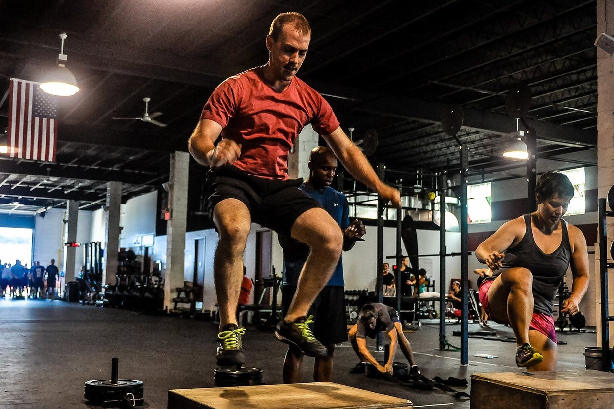 An athlete jumping onto a plyometric box in a gym
