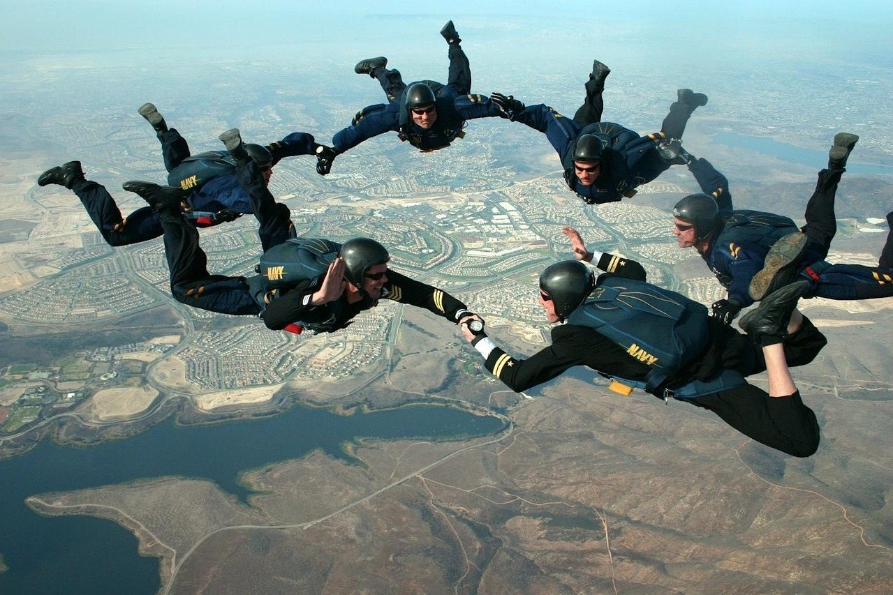 Navy skydivers form a circle mid-air over a landscape
