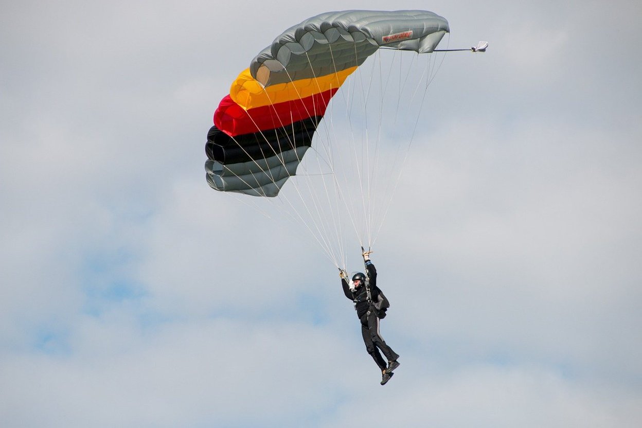 A skydiver under an open parachute against a blue sky