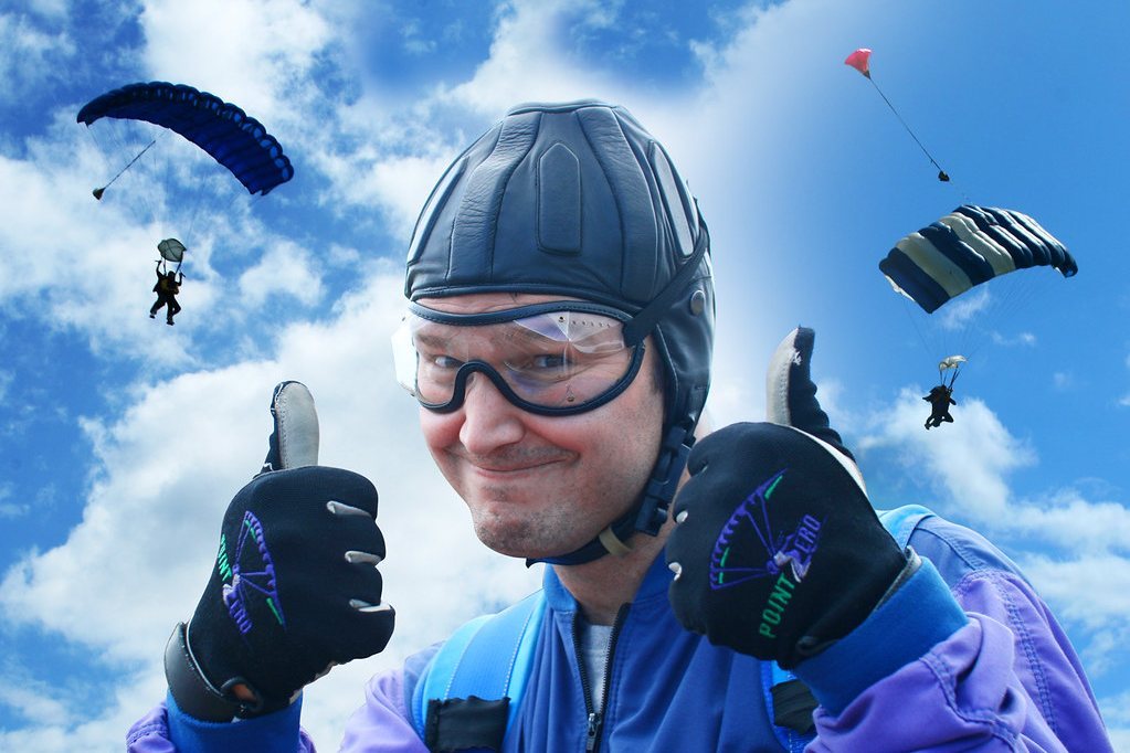 Skydiver giving thumbs up with parachutes in background