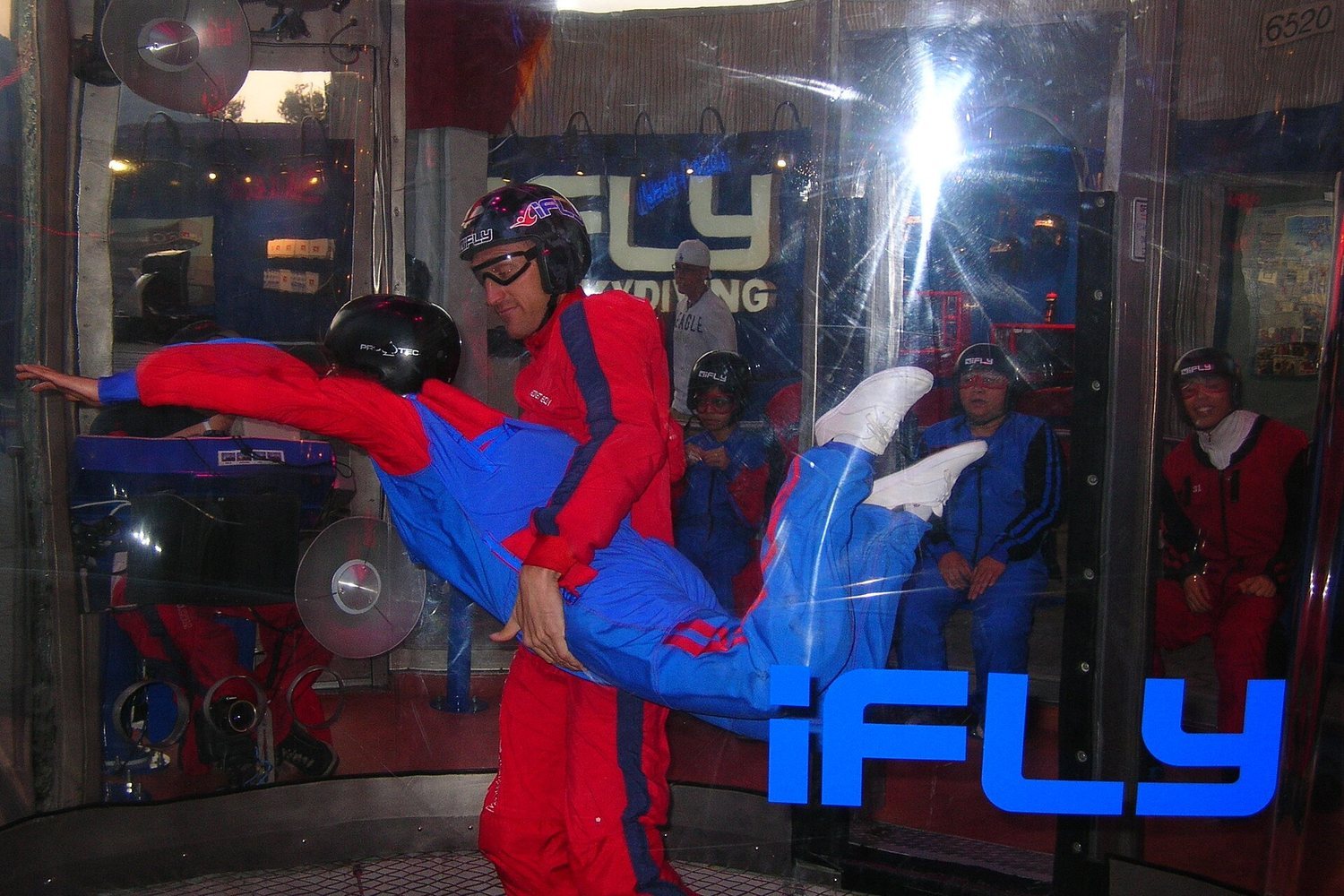 Indoor skydiving at iFLY with instructor assisting a flyer