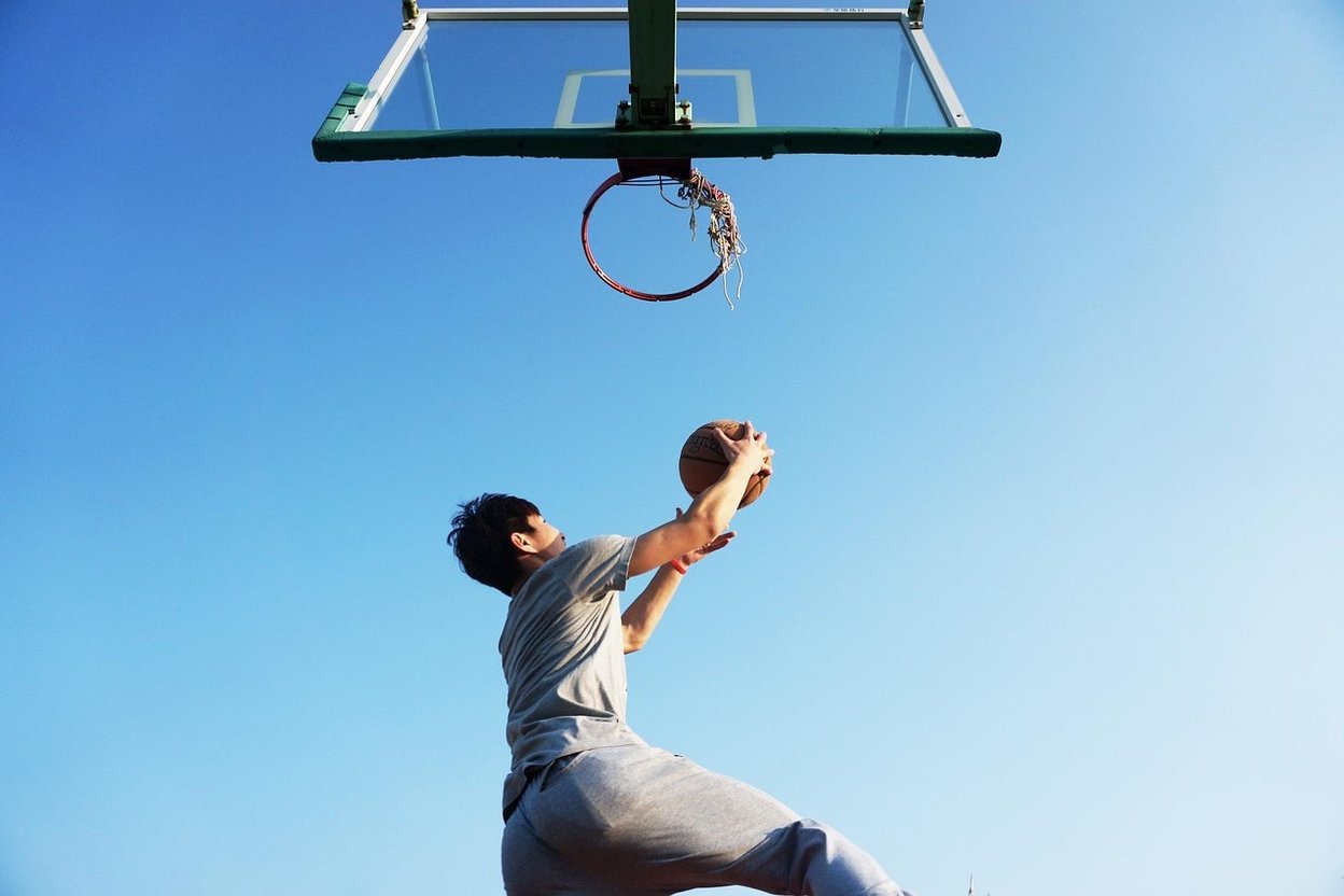 Athlete reaching up to slap the vanes of a Vertec vertical jump measuring pole in a gym