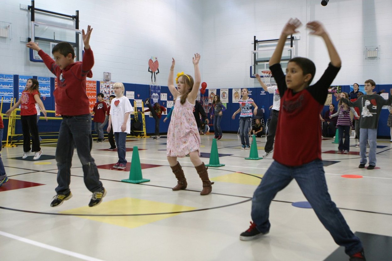 A group doing jumping jacks in an indoor gym