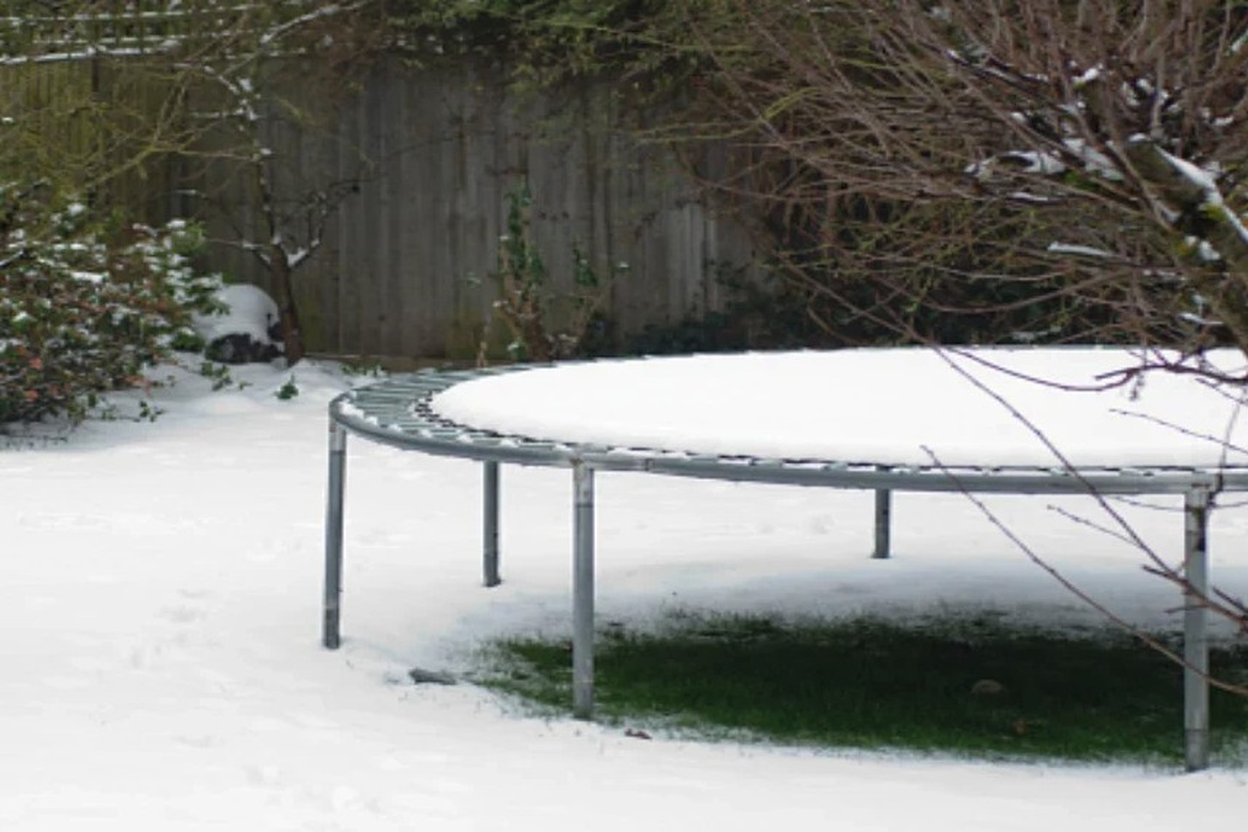 A backyard trampoline in a snowy yard