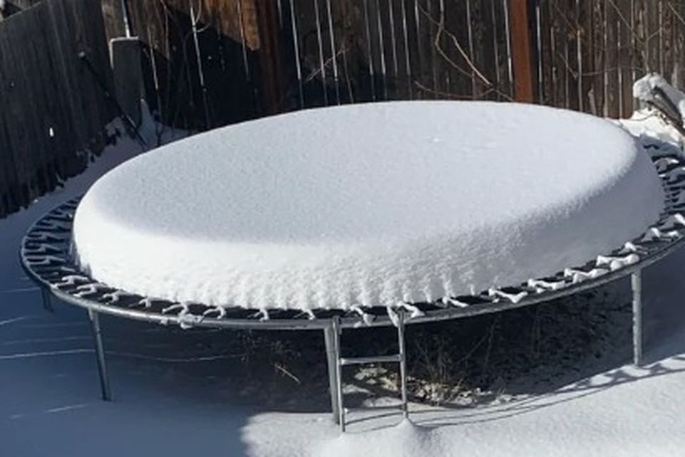 A thick slab of snow piled on a backyard trampoline mat